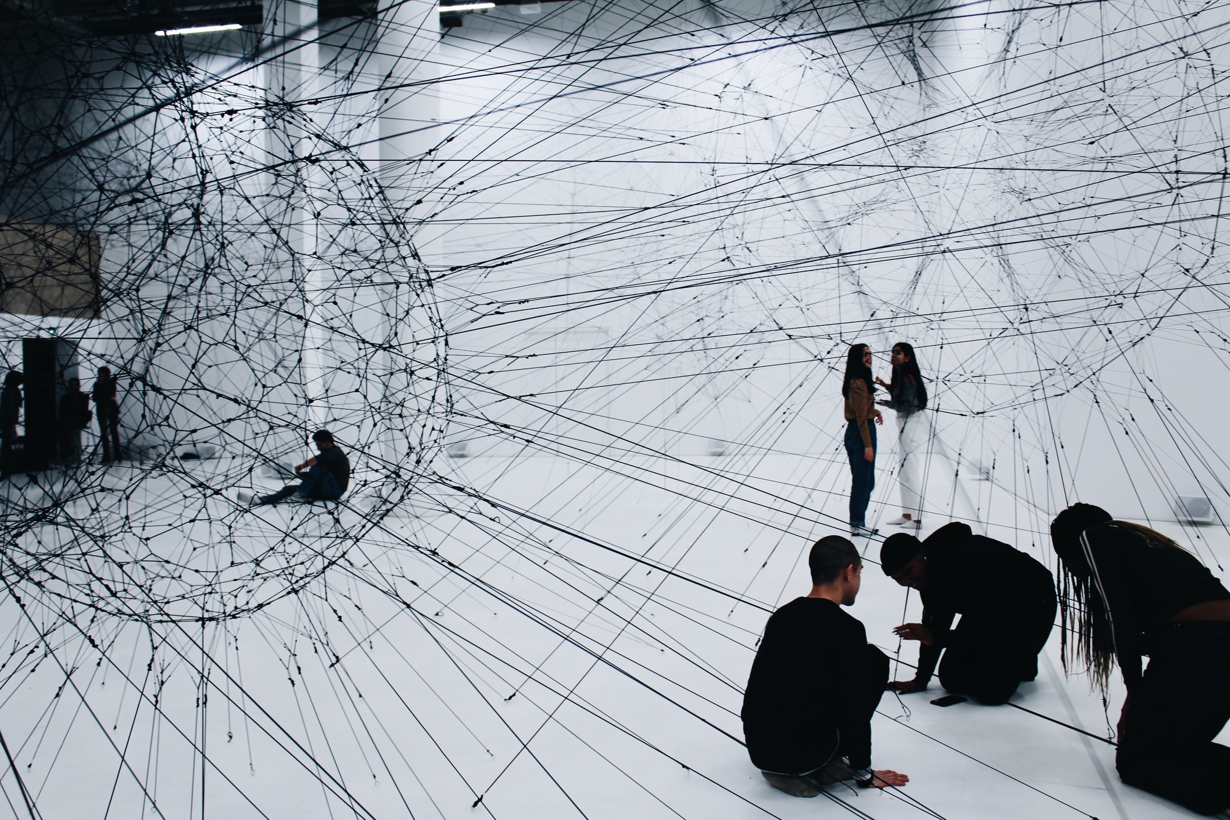 People sitting on the floor under a web of wires