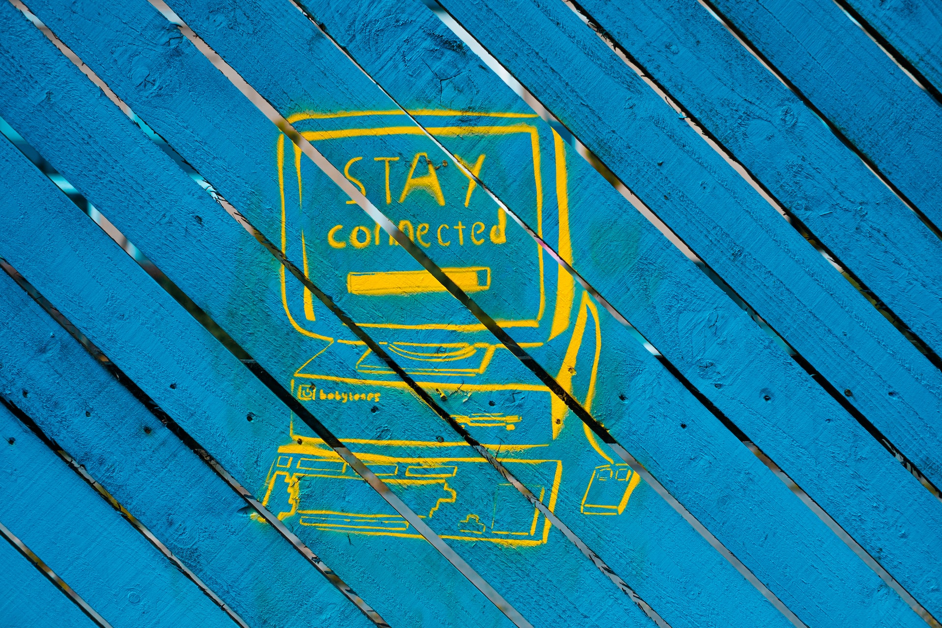 a computer stencil with the words stay connected on the screen on a blue wooden background.